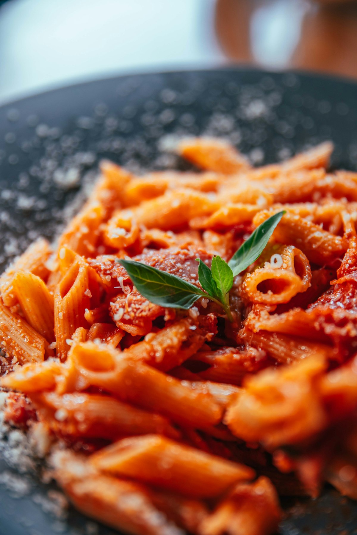 A close-up of saucy pasta with parmesan and fresh basil